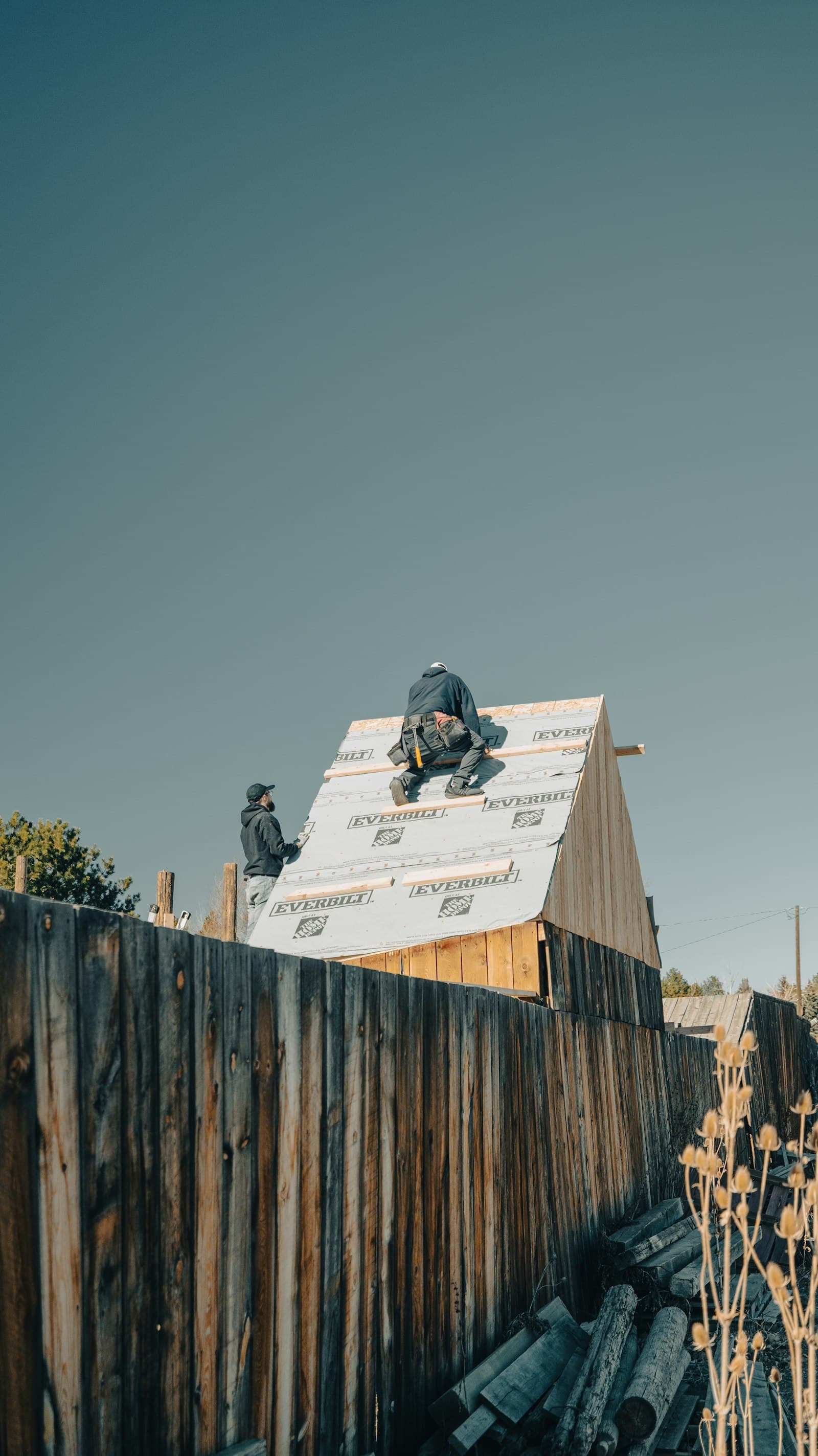 Roofing crew working on a residential roof under a clear sky