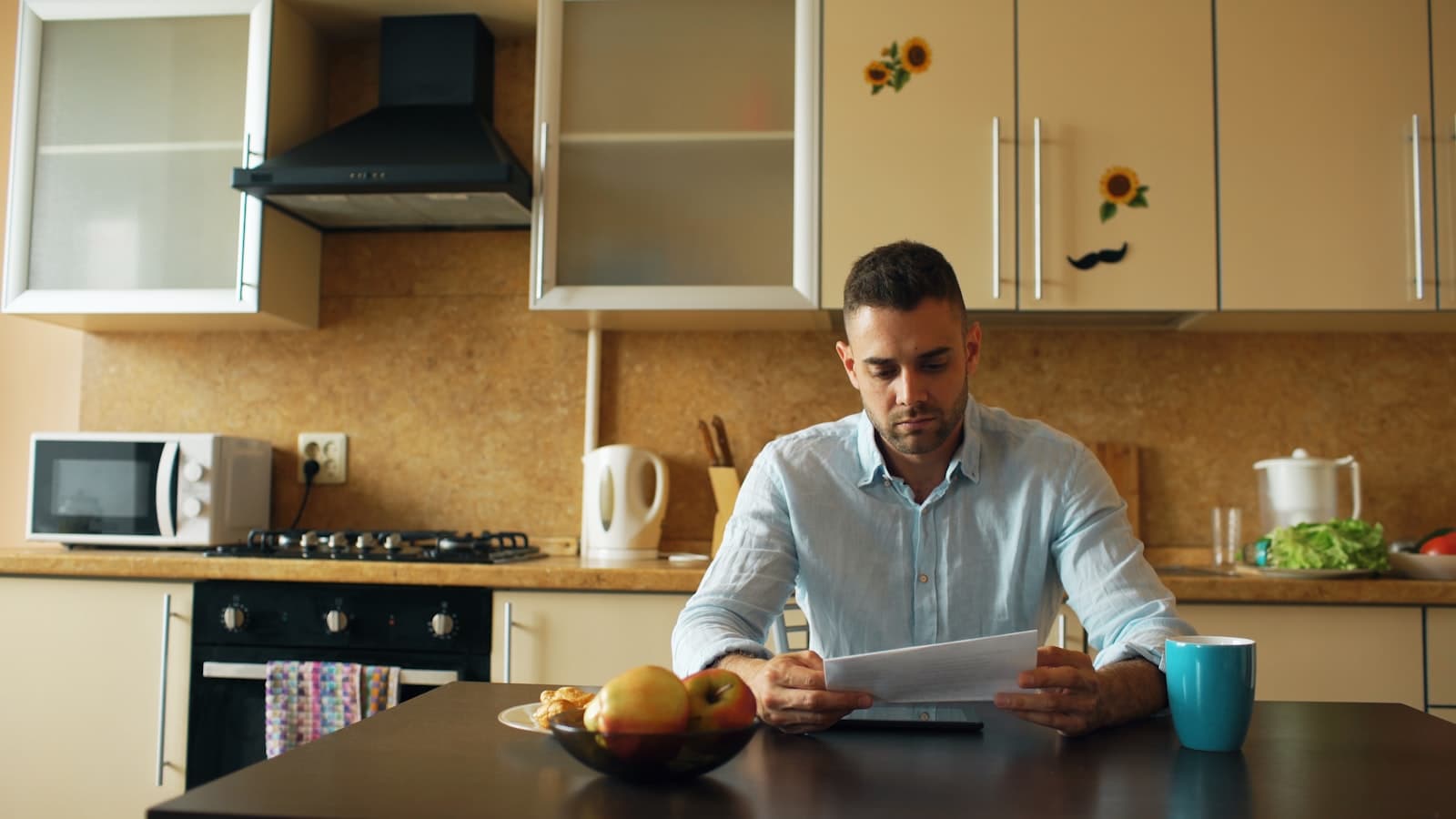 Man reviewing a document at a kitchen table, looking concerned