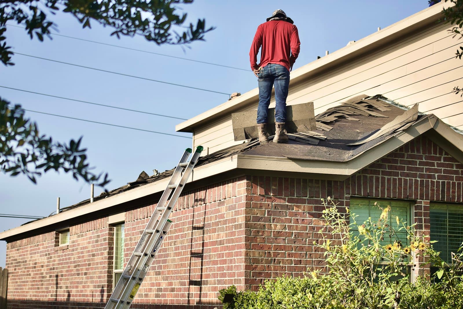 Worker standing on a residential rooftop surveying the surface