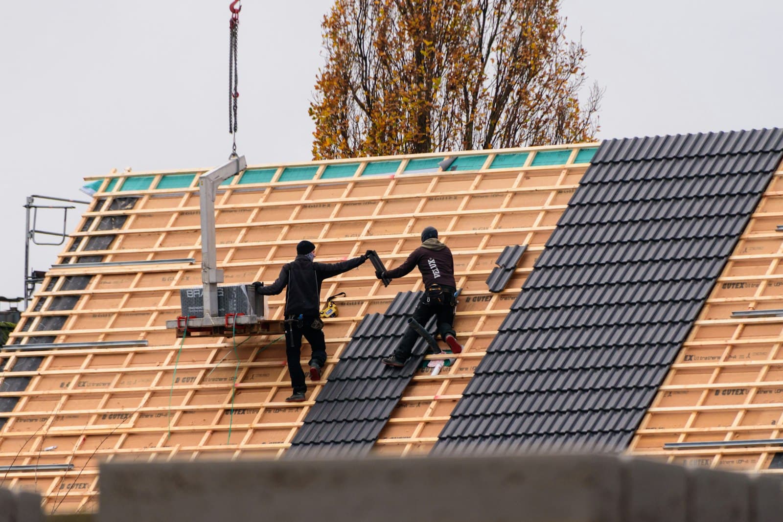 Roofing workers installing roof tiles on a new residential building